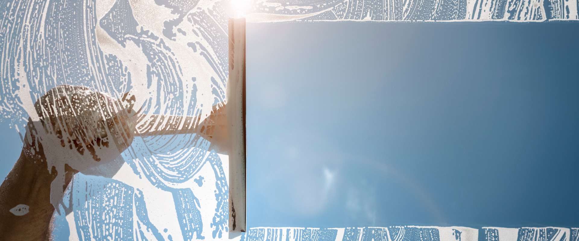 Fensterputzer mit einem Abzieher beim Reinigen eines Fensters