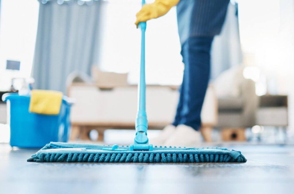Hauswirtschaft, Reinigung und Hausmädchen mit einem Mopp, um den Boden im Wohnzimmer eines Hauses zu reinigen. Weibliche Hausangestellte, Putzfrau und Hausfrau, die den Boden in ihrem Haus von Bakterien, Staub und Schmutz befreit.